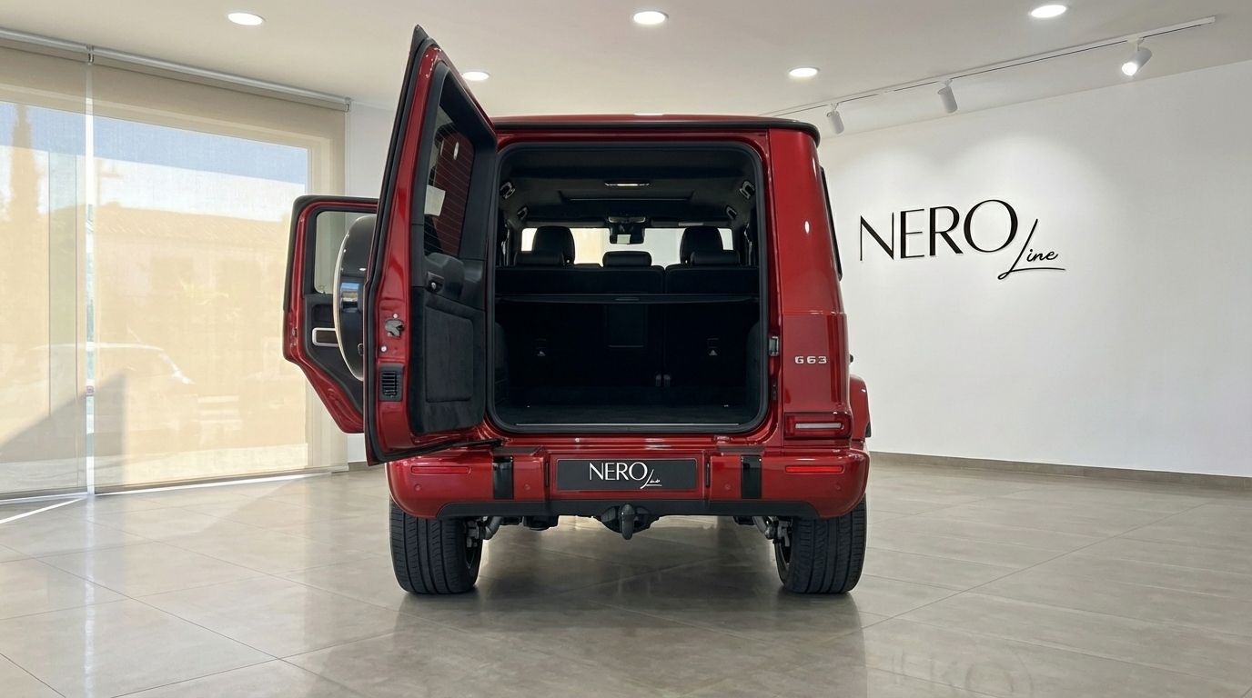 The glossy red 2022 Mercedes-Benz G63 AMG is shown from the rear with its trunk and passenger door open in Alicante.