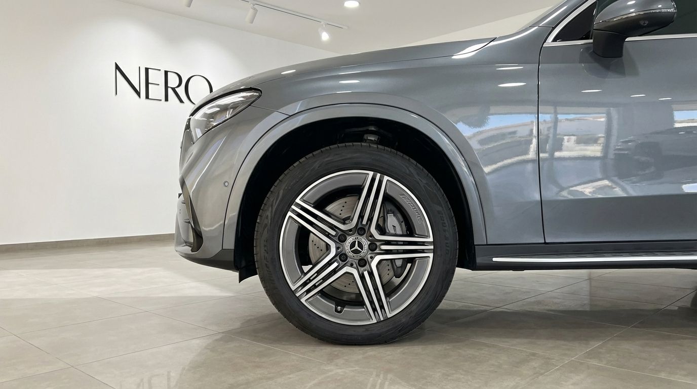 The metallic grey Mercedes-Benz GLC 200's front wheel and side profile are showcased in a showroom in Alicante.