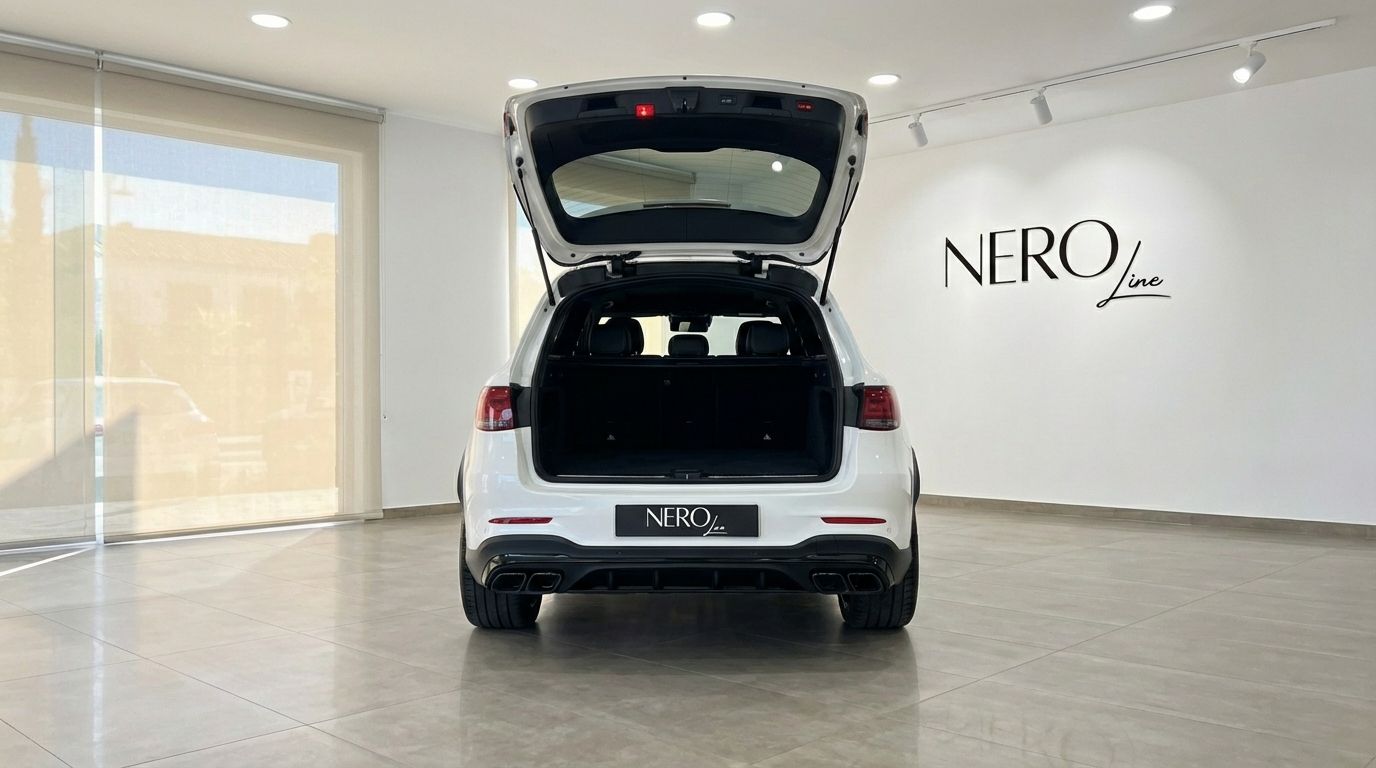 The rear view of a white Mercedes-Benz GLC 63 S AMG with its trunk open, parked in a showroom in Marbella.