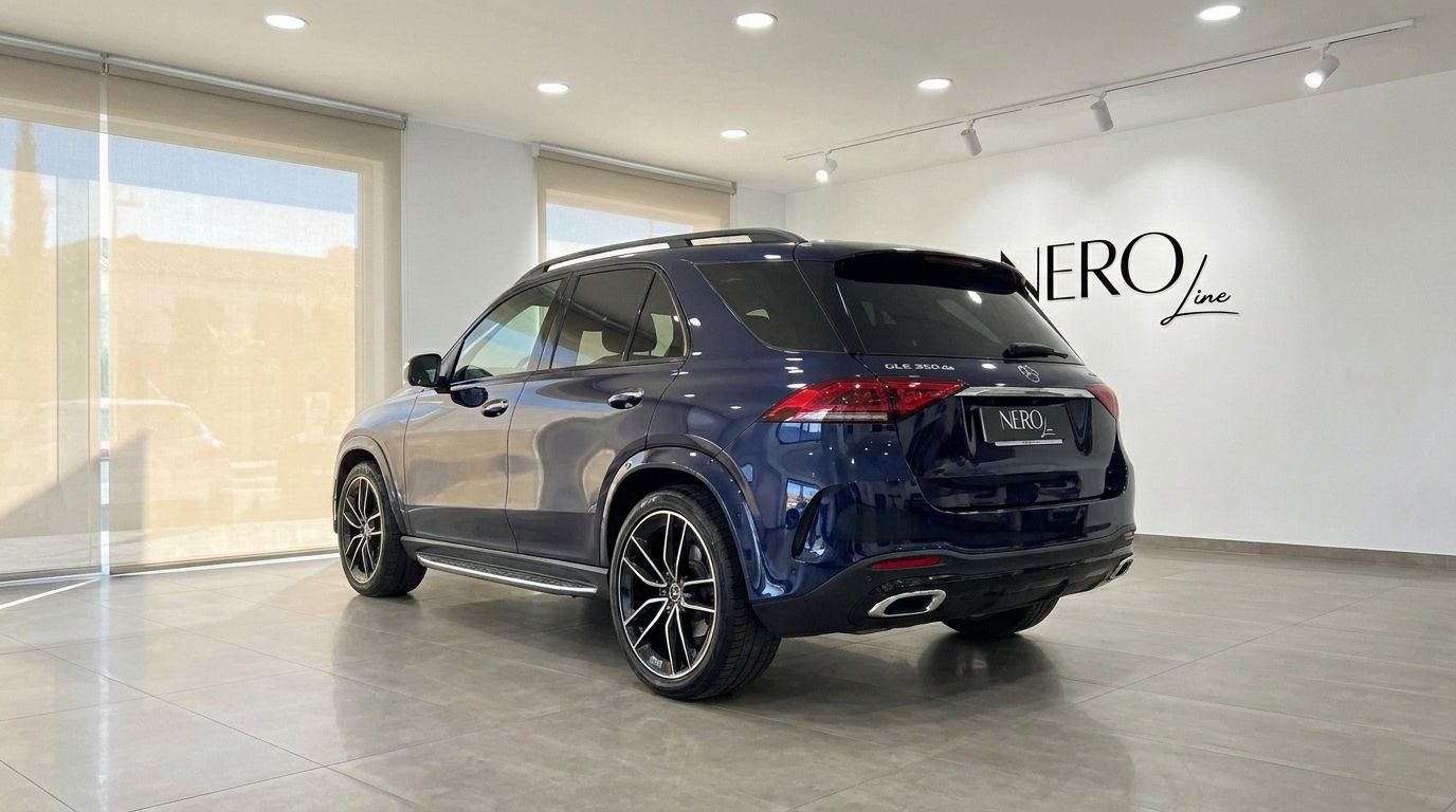 El Mercedes-Benz GLE 350de 4MATIC AMG azul oscuro se muestra desde el ángulo trasero tres cuartos en una sala de exposición en Alicante.