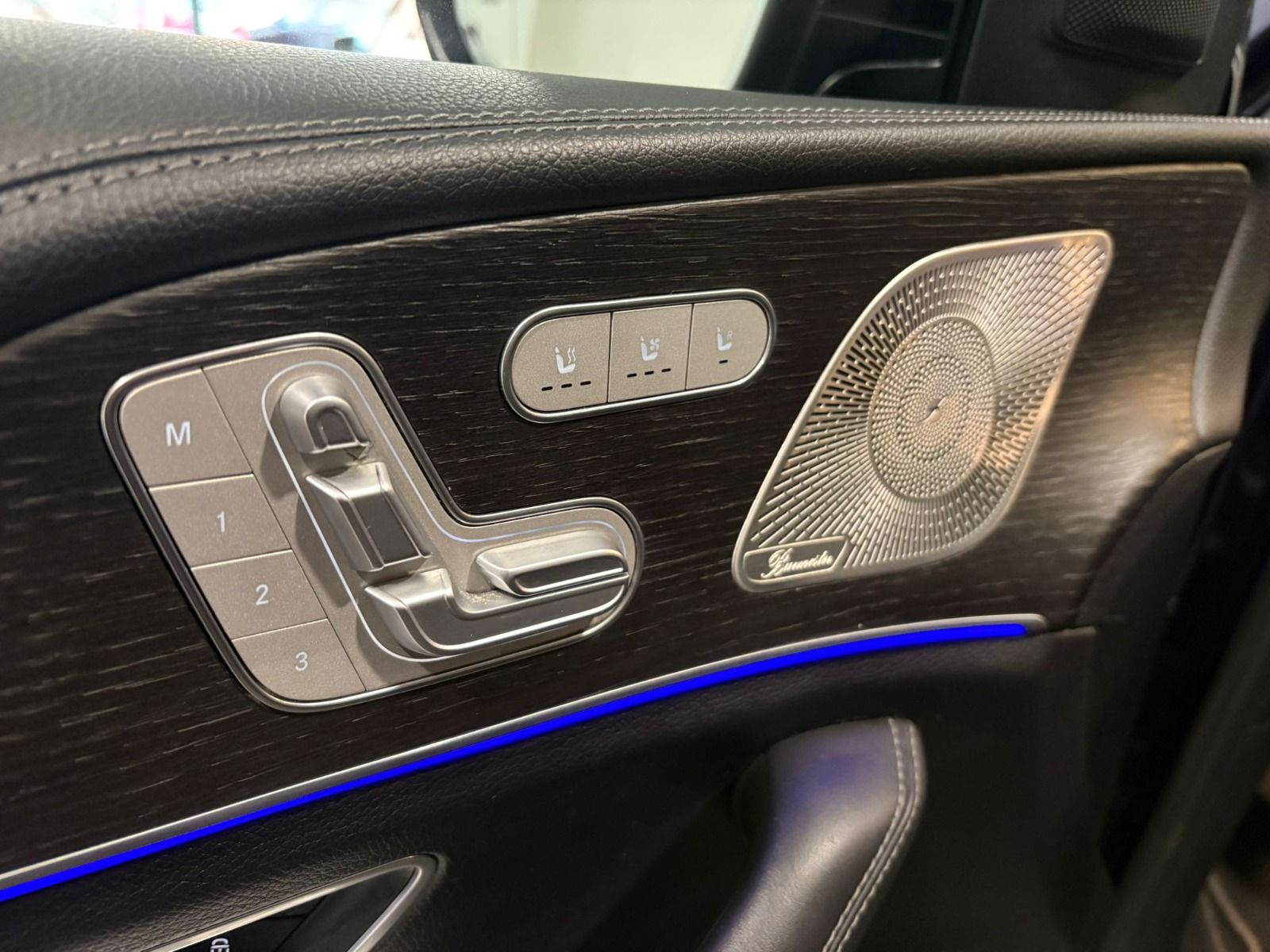 Panel de puerta del Mercedes-Benz GLE 350de mostrando controles de asiento, altavoz Burmester e iluminación ambiental azul.