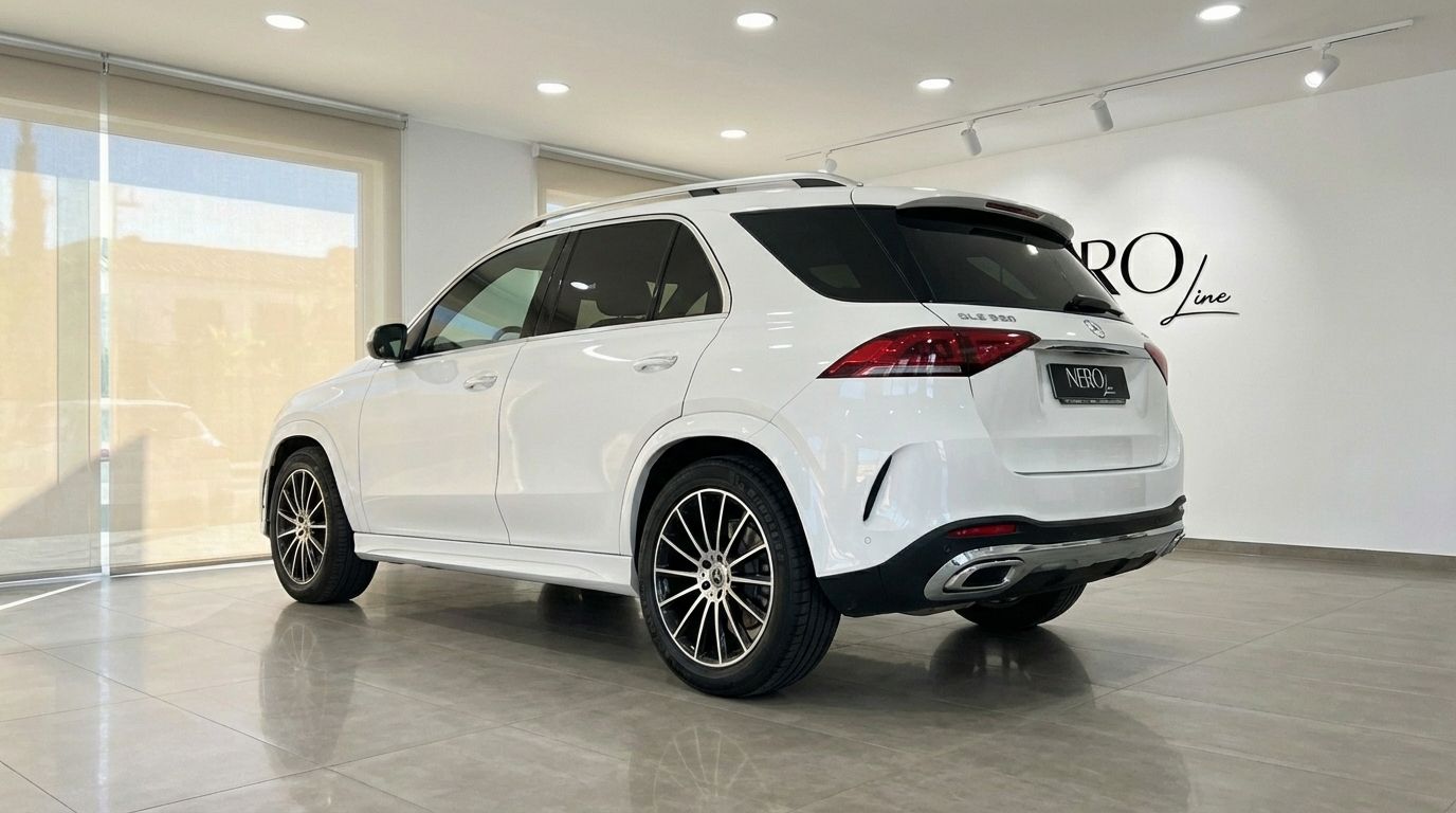 A white Mercedes-Benz GLE 350e AMG SUV, seen from the rear three-quarter angle, parked indoors in Alicante.
