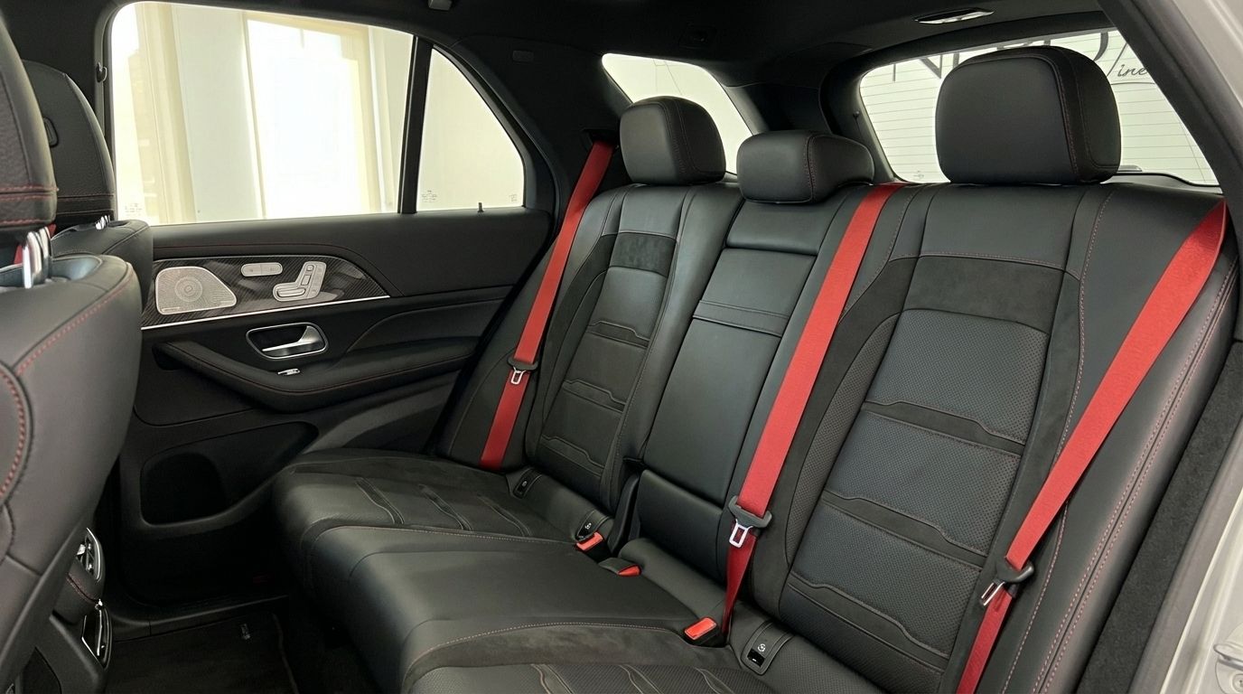 The luxurious rear interior of the Mercedes-Benz GLE 63s AMG in Alicante, featuring black leather seats with red stitching and vibrant red seatbelts.