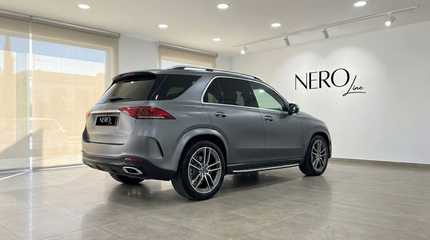 The matte Selenite Grey Magno 2022 Mercedes-Benz GLE AMG Line SUV is showcased from the rear three-quarter view in a Mallorca showroom.