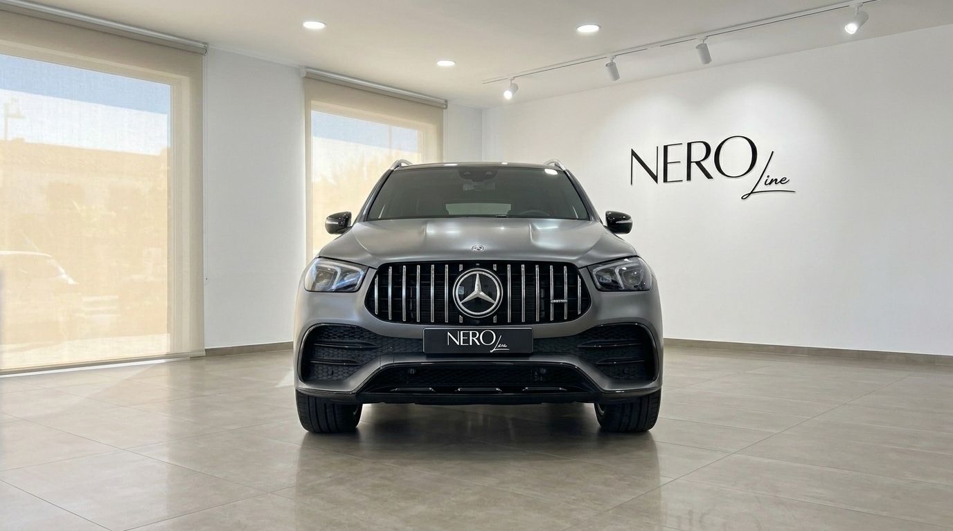 The matte Selenite Grey Magno Mercedes-Benz GLE AMG Line is showcased from a direct front view in a bright showroom in Mallorca.