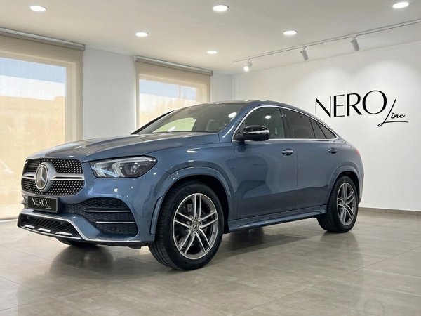 Mercedes-Benz GLE Coupe — Showroom in Mallorca The 2022 Mercedes-Benz GLE Coupe in metallic steel blue, shown from a front three-quarter angle in a showroom in Mallorca.
