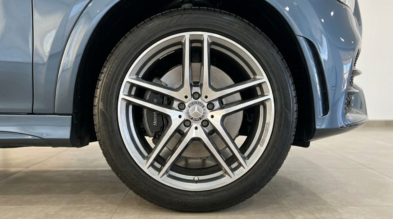 The Mercedes-Benz GLE Coupe in Mallorca, showcasing its metallic steel blue body and a detailed view of its elegant multi-spoke front wheel.