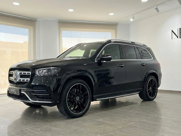Mercedes-Benz GLS 450 4Matic — Vista showroom Madrid El SUV Mercedes-Benz GLS 450 4Matic negro brillante se exhibe en vista tres cuartos frontal en un luminoso concesionario de Madrid.