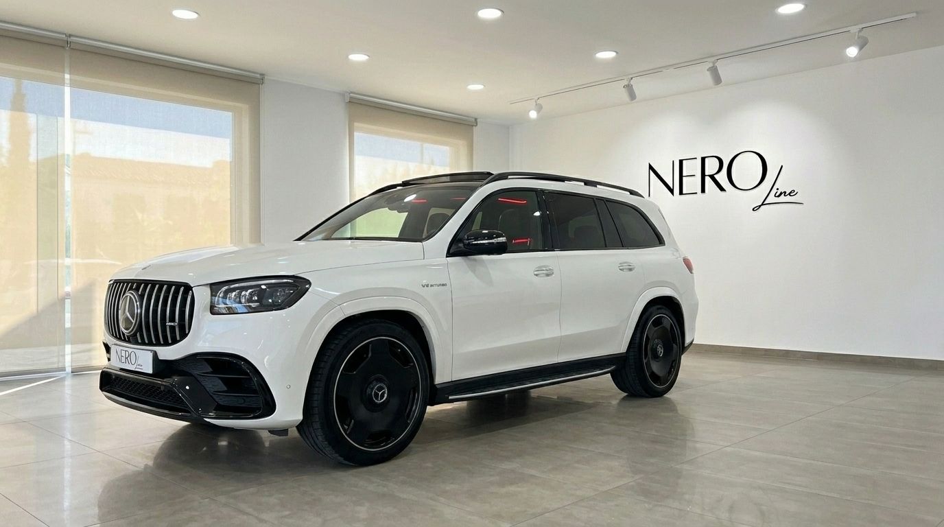 The white Mercedes-Benz GLS 63 AMG is showcased from a front three-quarter angle in a bright showroom in Alicante.