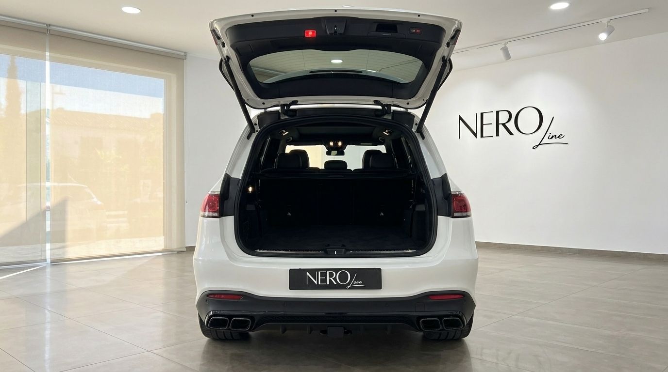 The white Mercedes-Benz GLS 63 AMG SUV from the rear, showcasing its open trunk and spacious cargo area in Alicante.