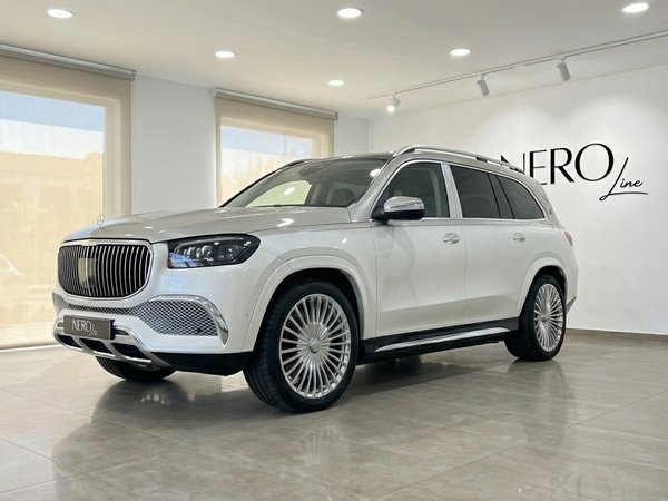 Mercedes-Benz GLS680 MAYBACH — Showroom Madrid El Mercedes-Benz GLS680 MAYBACH 2024 blanco perla se exhibe desde una vista tres cuartos frontal en un concesionario de Madrid.