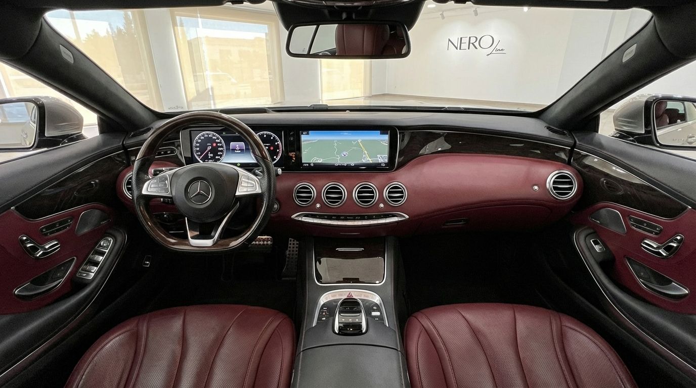 The luxurious interior of the Mercedes-Benz S500 Coupe in Alicante, featuring a detailed view of the dashboard, steering wheel, and rich red leather seats.