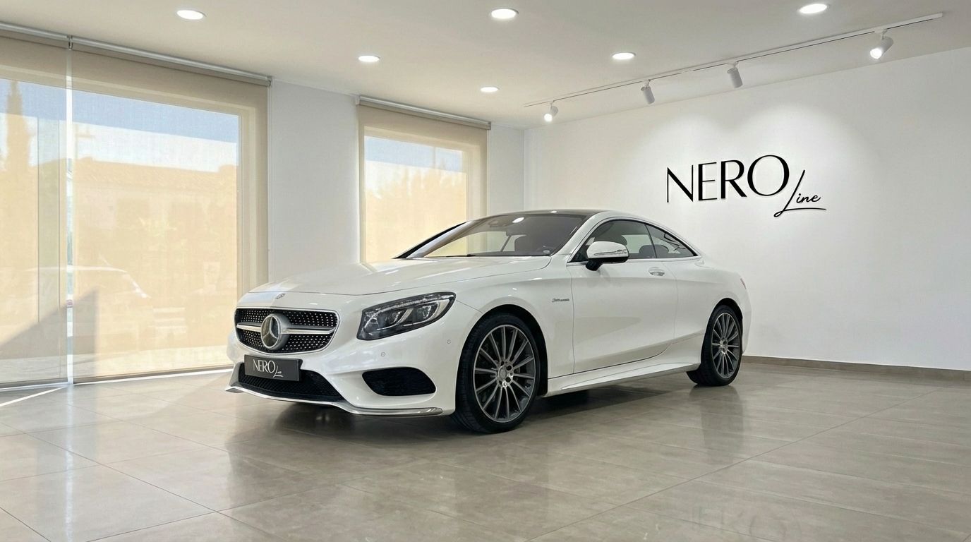 A white Mercedes-Benz S500 Coupe is showcased in a modern Alicante showroom, captured from a front three-quarter angle.