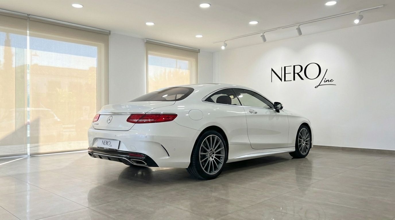 The white Mercedes-Benz S500 Coupe is showcased from a rear three-quarter angle in a bright showroom in Alicante.