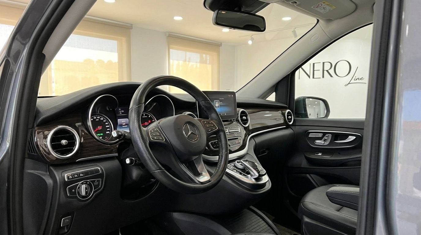 The luxurious cockpit of the Mercedes-Benz V-Class 250d is visible, featuring the steering wheel, dashboard, and infotainment screen in Benidorm.