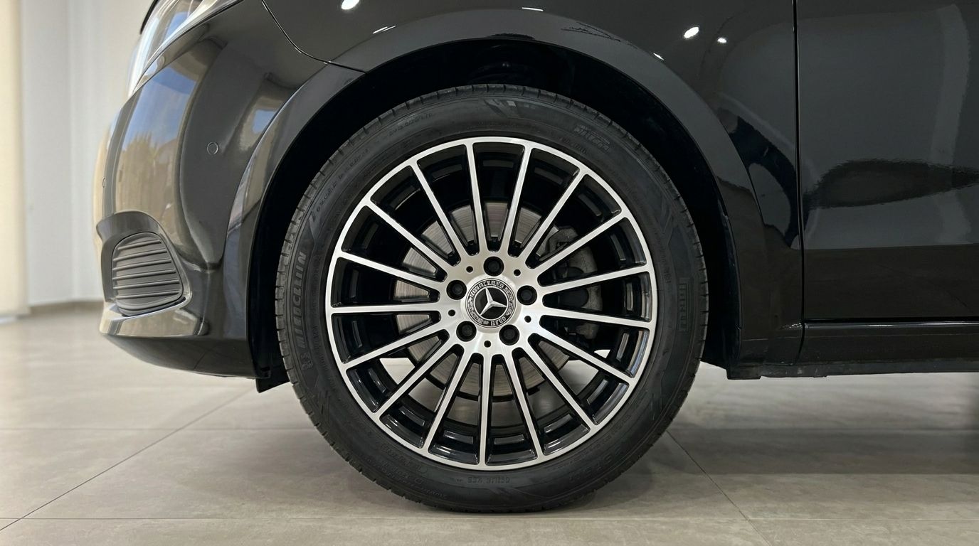 The front wheel and fender of the black Mercedes-Benz V-Class 250d are visible, showcasing its elegant alloy rim in Alicante.