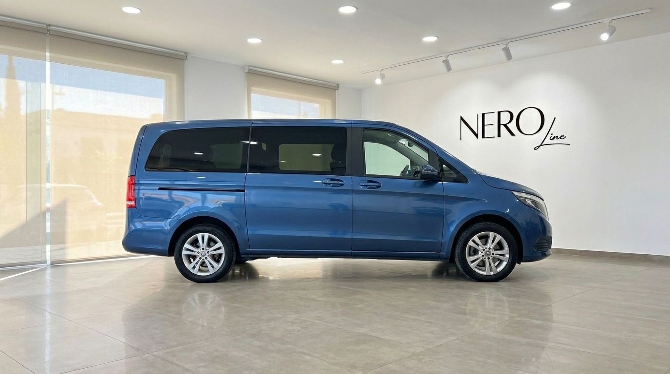 A metallic blue Mercedes-Benz V-Class 300d Extralang van is shown in a side profile view, parked inside a showroom in Mallorca.