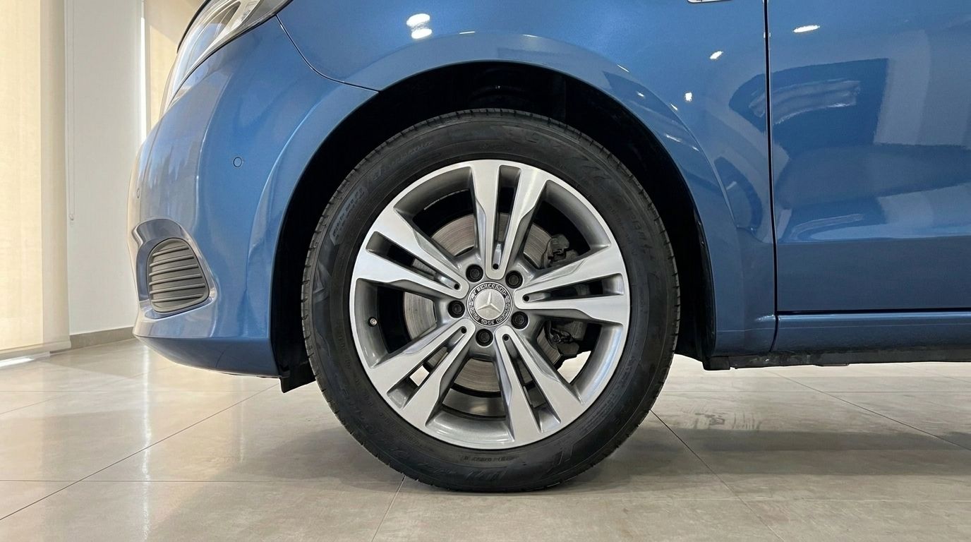 The metallic blue Mercedes-Benz V-Class 300d Extralang's front wheel and lower body are visible on a tiled floor in Mallorca.