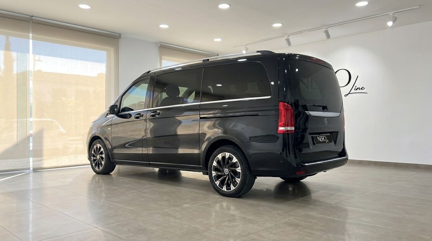 Ein eleganter glänzend schwarzer Mercedes-Benz V220 (8 Sitze), aus der hinteren Dreiviertelansicht in einem hellen Showroom in Ibiza.