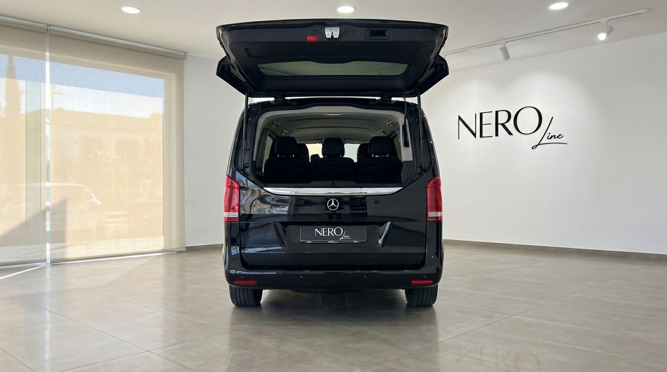 Der schwarze Mercedes-Benz V220 (8 Sitze) ist von hinten mit geöffnetem Kofferraum zu sehen, der die geräumigen Innensitze in einem Ausstellungsraum auf Ibiza zeigt.