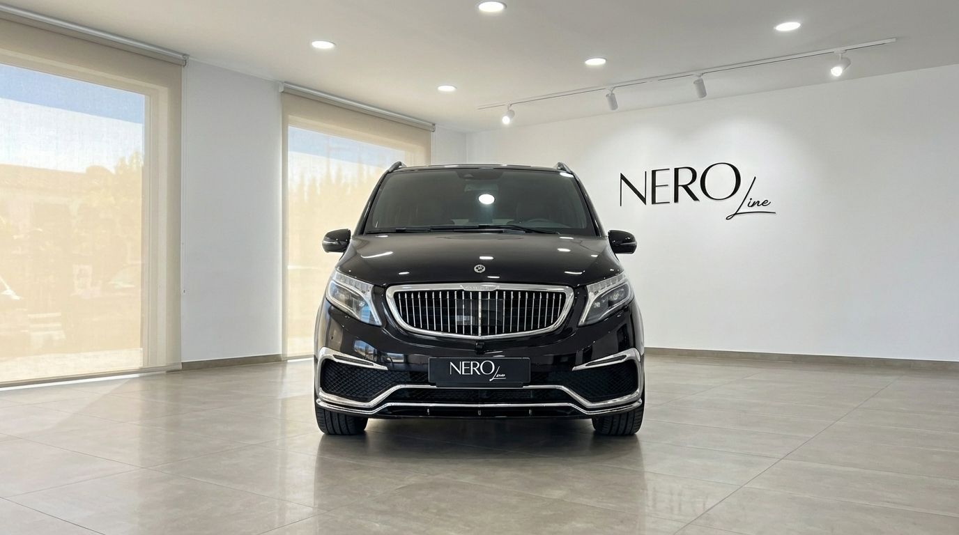 La furgoneta de lujo Mercedes-Benz V250d negra está aparcada de frente en un luminoso concesionario en Madrid.