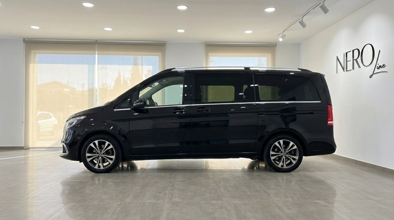 Una furgoneta de lujo Mercedes-Benz V250d negra está estacionada en el interior, mostrando su elegante perfil lateral en Madrid.