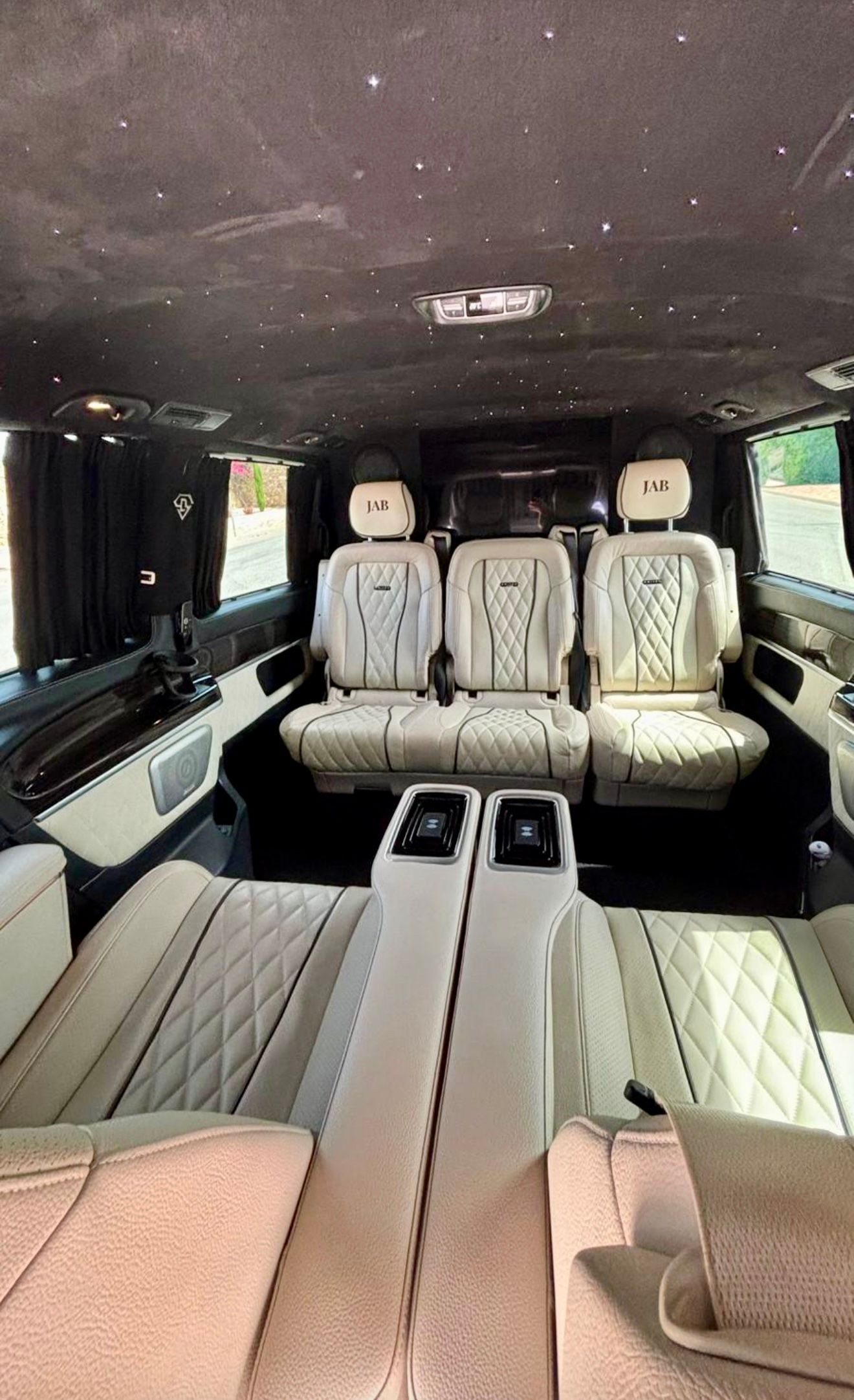 El opulento habitáculo trasero del Mercedes-Benz V250d en Madrid, con asientos VIP de cuero acolchado claro y un techo estrellado.