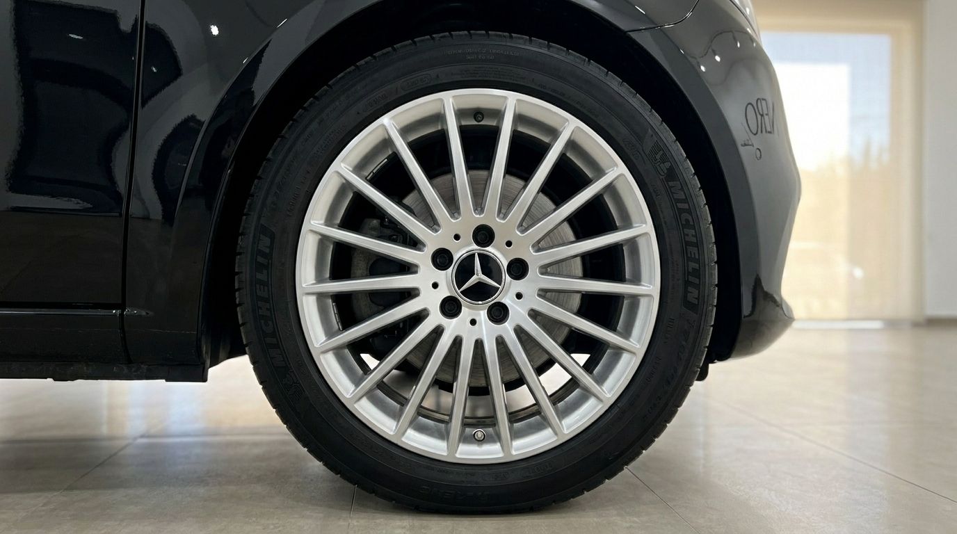 Primer plano de la rueda delantera y el guardabarros del Mercedes-Benz V300, mostrando su llanta plateada de radios múltiples en Madrid.