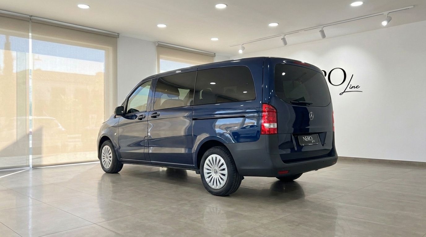 The dark blue Mercedes-Benz Vito Tourer 119 CDI is shown from a rear three-quarter angle, parked indoors in a bright showroom.