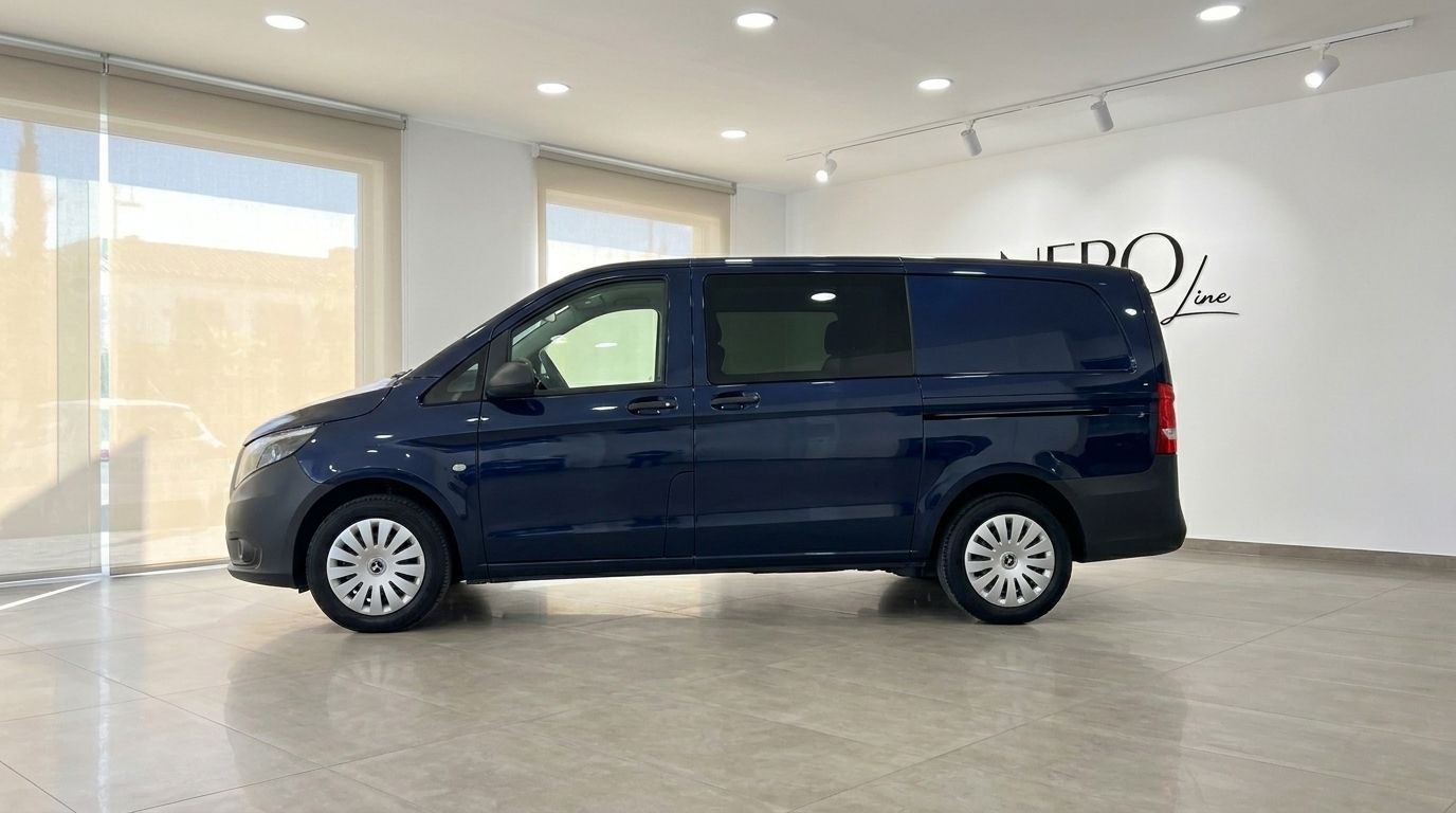 The dark blue Mercedes-Benz Vito Tourer is parked sideways in a bright, modern showroom with large windows.