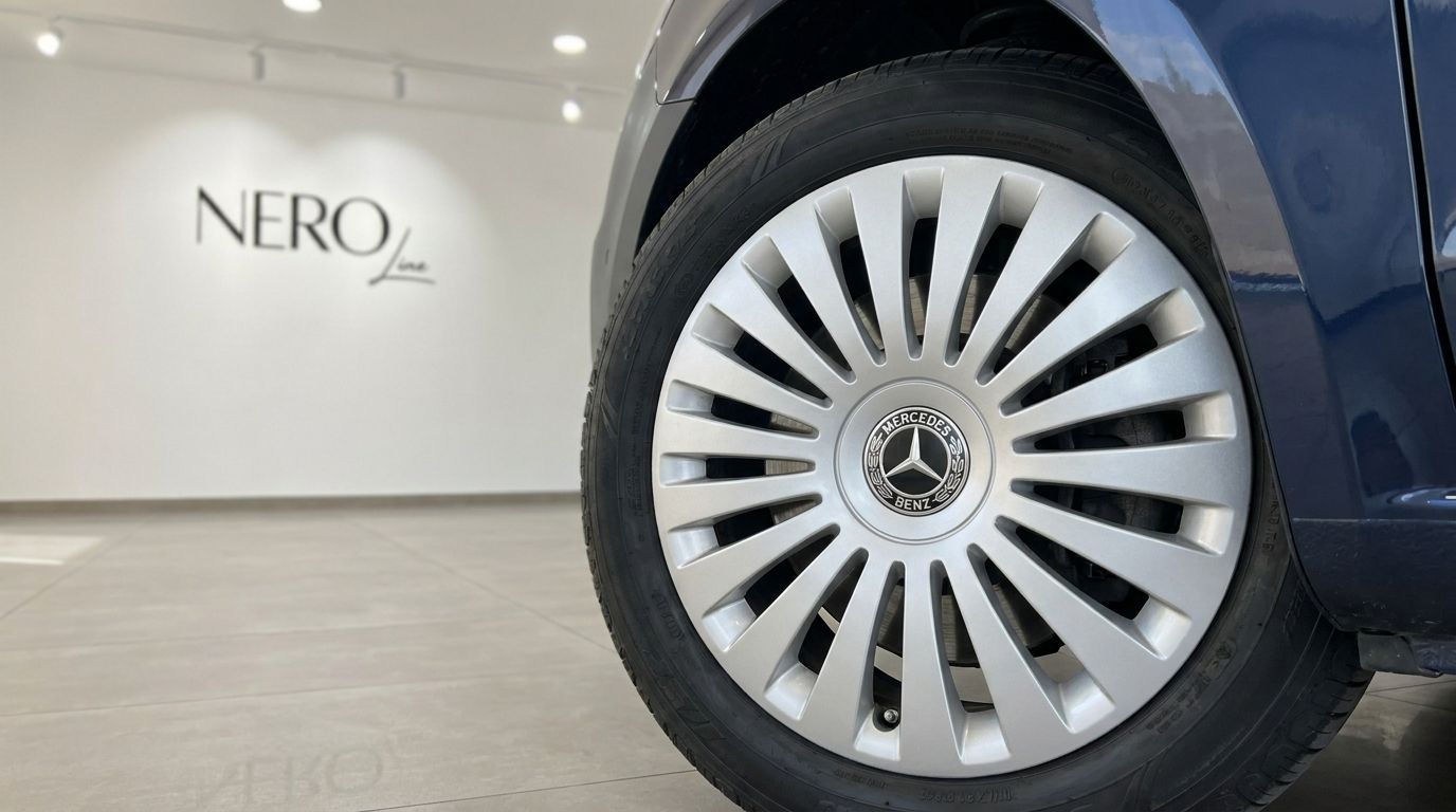 Close-up of the Mercedes-Benz Vito Tourer's front wheel and tire, featuring the hubcap logo, with the NERO Line branding in the background.