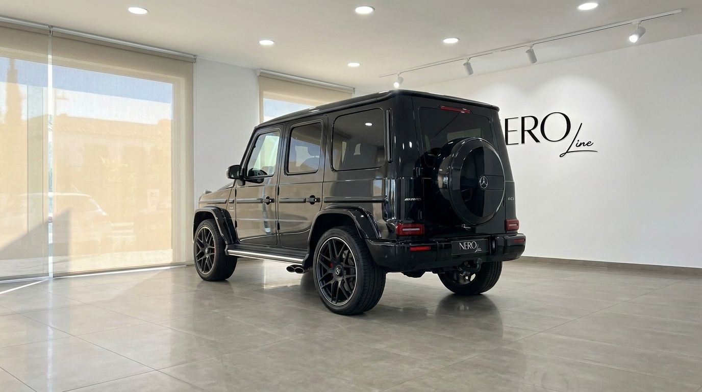 The glossy black Mercedes G63 AMG is displayed from a rear three-quarter angle inside a modern showroom in Madrid.