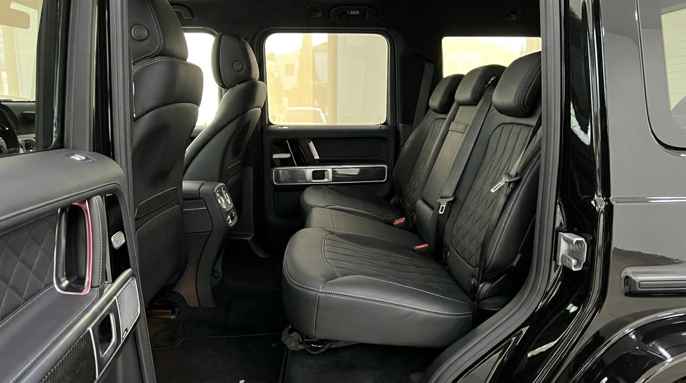 The rear interior of the Mercedes G63 AMG in Madrid, featuring luxurious black leather seats with white stitching and detailed door panels.