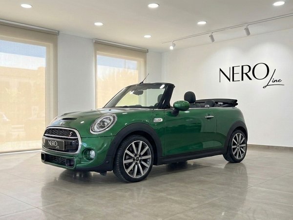 Mini Cooper S Cabrio — Convertible in Mallorca A vibrant green Mini Cooper S Cabrio, with its convertible top down, is showcased in a modern showroom in Mallorca.