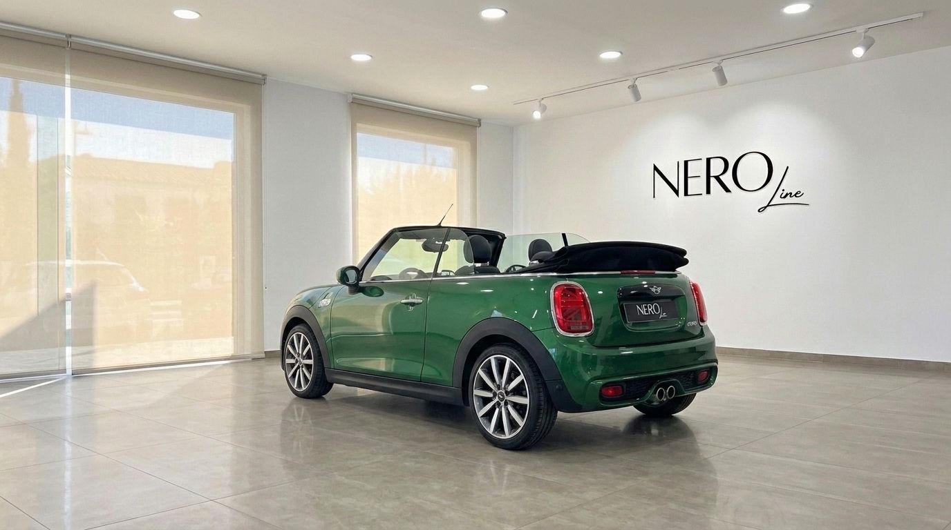The green 2021 Mini Cooper S Cabrio is parked in a showroom, showcasing its rear three-quarter view with the top down in Mallorca.