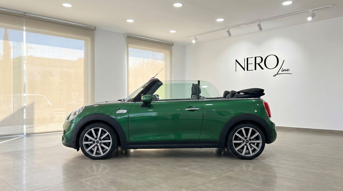 The green Mini Cooper S Cabrio, with its convertible top folded down, is showcased from a side profile view in a Mallorca showroom.