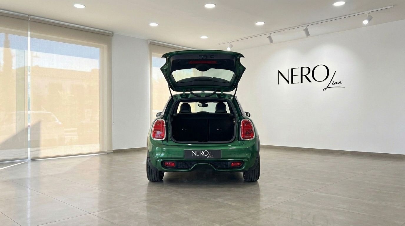 The green Mini Cooper S Cabrio is shown from the rear with its trunk open, parked in a bright showroom in Mallorca.