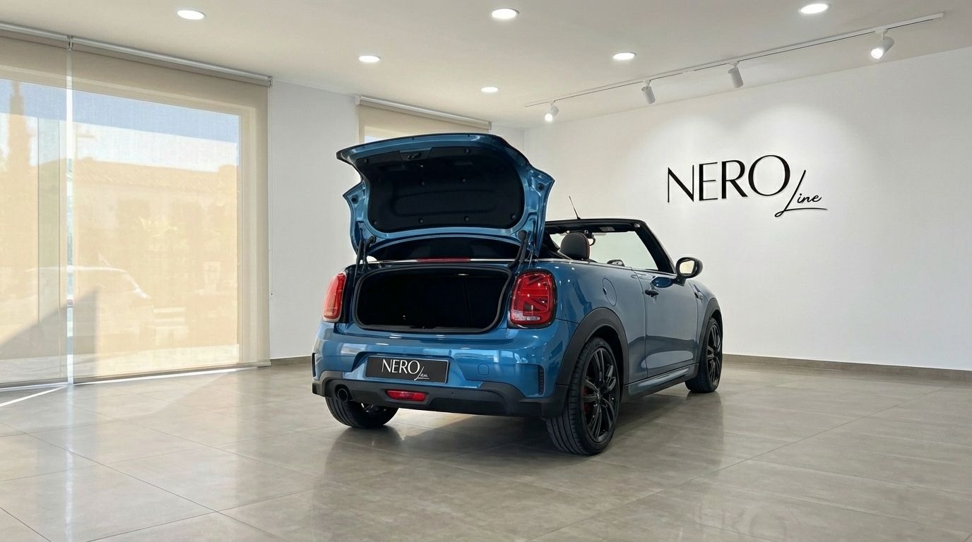 The metallic blue Mini Cooper John Works Convertible is shown from the rear with its trunk open, parked in a showroom in Ibiza.