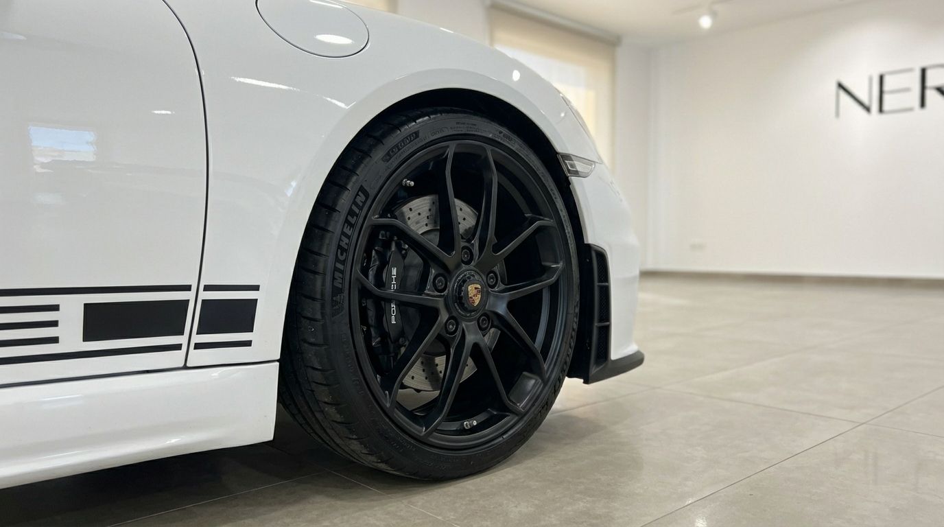 El Porsche 718 SPIDER RS blanco presenta una llanta negra multirradio y distintivas franjas laterales negras, exhibido en Madrid.