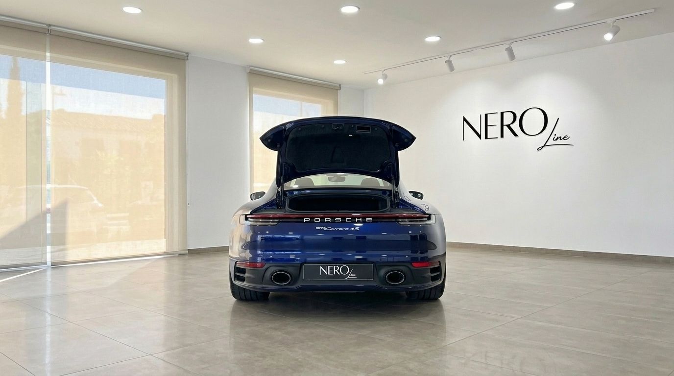 Heckansicht eines blauen Porsche 911 Carrera 4S mit geöffnetem Kofferraum, geparkt in einem Showroom auf Ibiza.