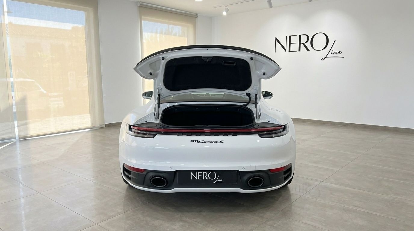 Porsche 911 Carrera S 992 blanco desde la parte trasera con el compartimento del motor abierto, en un showroom de NEROline en Madrid.