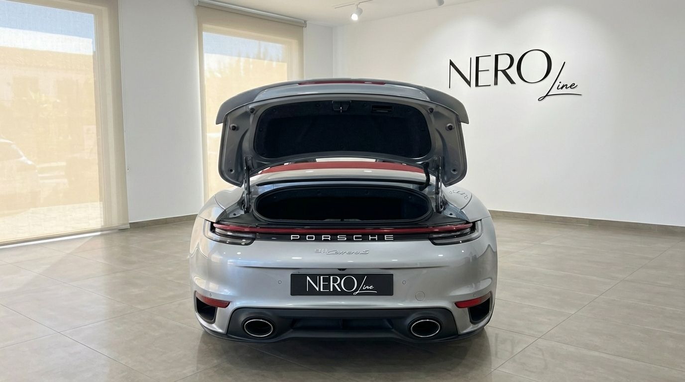 Rear view of a silver Porsche 911 Turbo S Cabriolet with its trunk open, showcasing storage in a showroom in Barcelona.