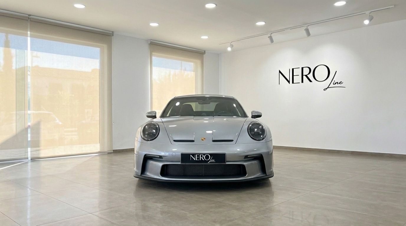 La Porsche 992 GT3 argento metallizzato lucido è parcheggiata frontalmente in uno showroom interno luminoso a Ibiza.