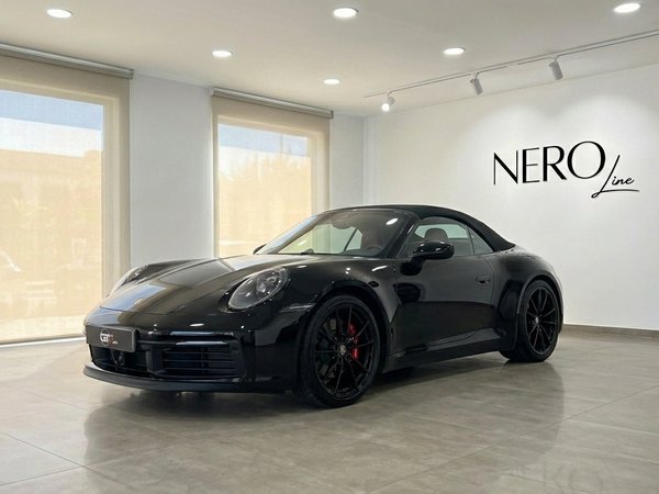 Porsche Carrera 4S Convertible — Showroom Madrid El Porsche Carrera 4S Convertible negro de 2021 se exhibe desde un ángulo frontal tres cuartos en un luminoso showroom de Madrid.