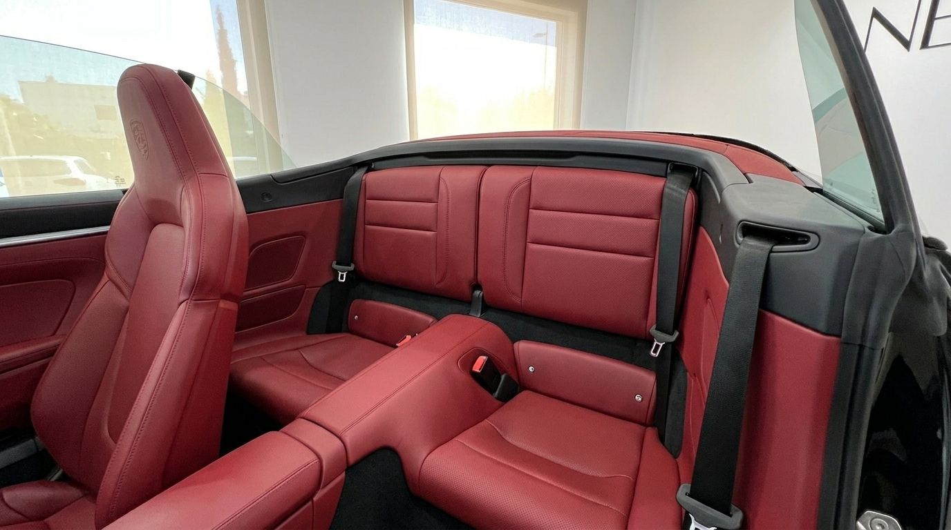 Los lujosos asientos traseros de cuero rojo y el respaldo del asiento del pasajero delantero en el Porsche Carrera 4S Convertible en Madrid.
