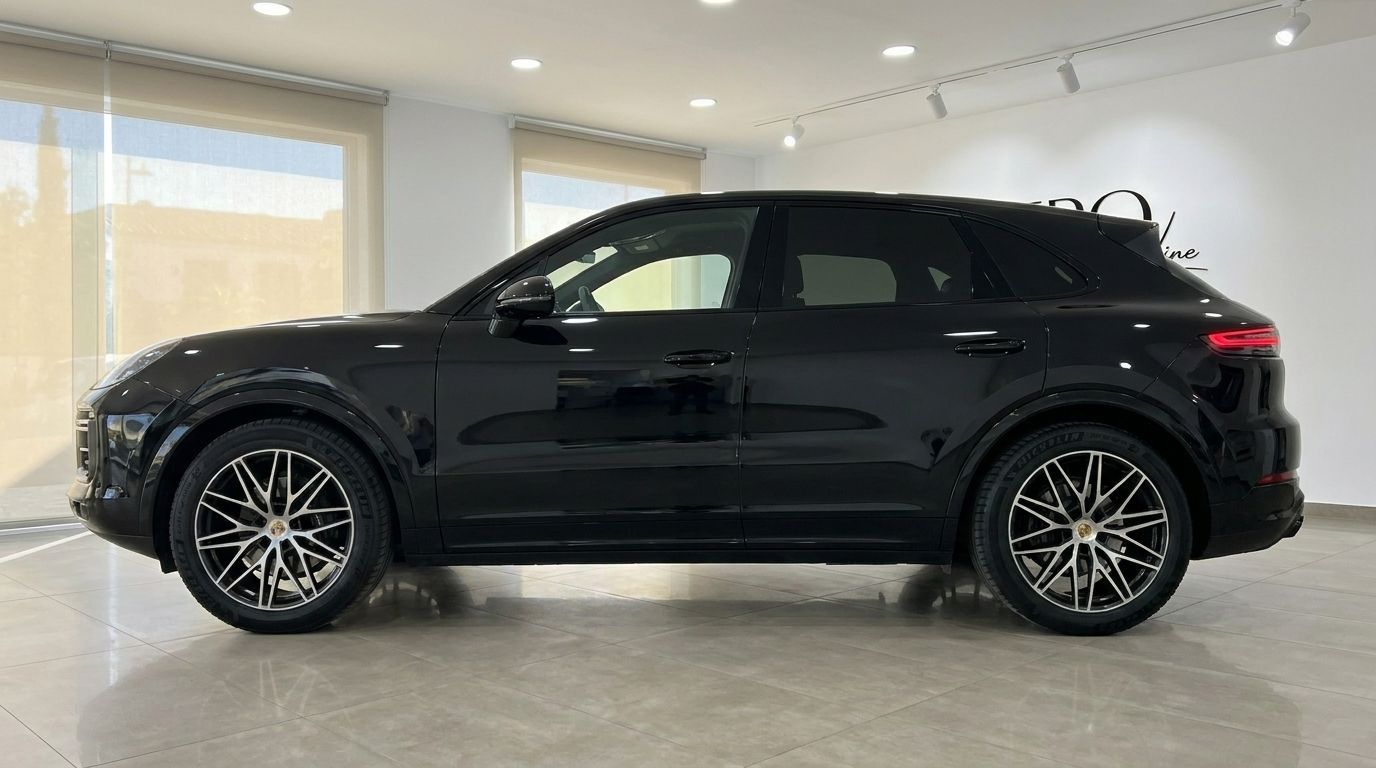 The sleek black Porsche Cayenne SUV is showcased in a side profile view within a showroom in Alicante.