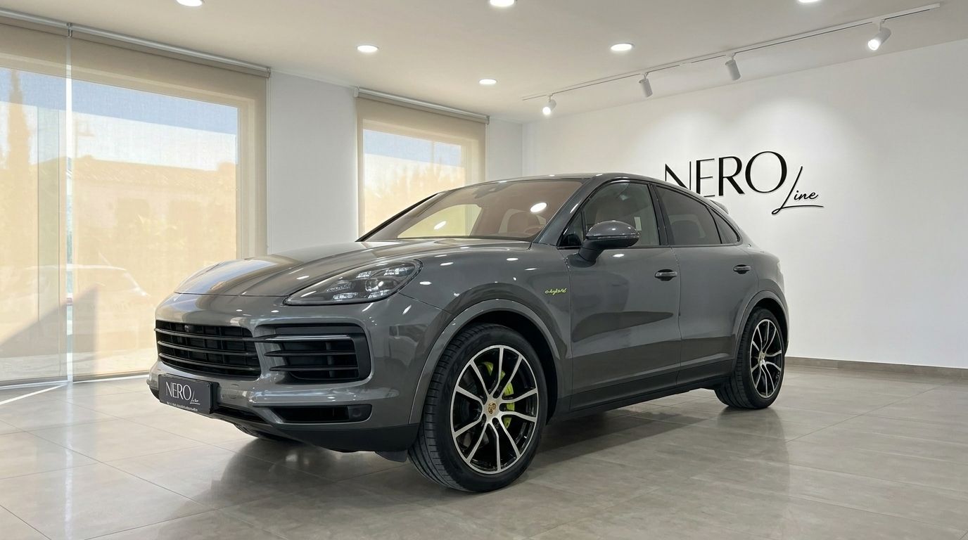 The gloss Quarzite Grey Metallic 2022 Porsche Cayenne is showcased from a front three-quarter angle inside a modern showroom in Alicante.