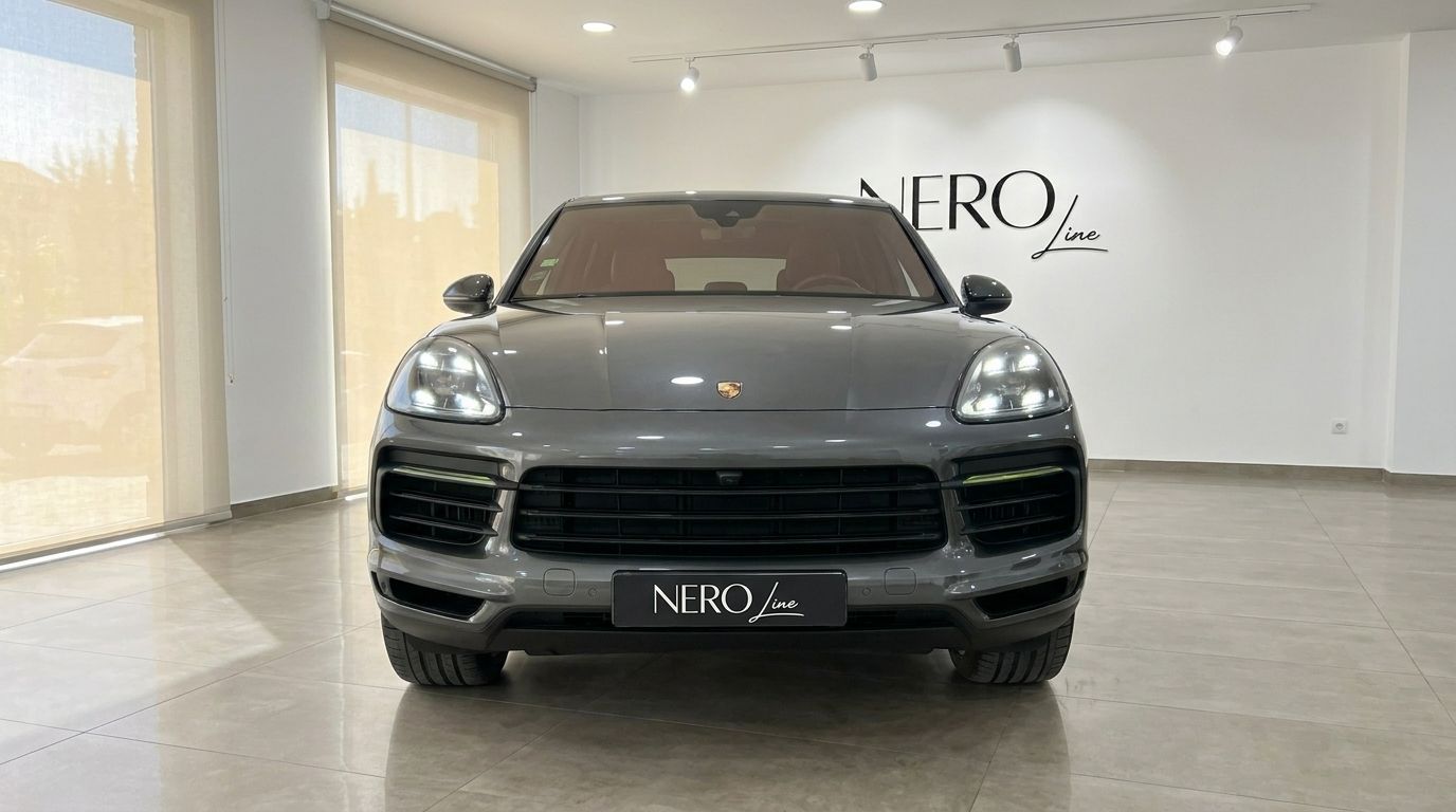 The 2022 Porsche Cayenne in gloss Quarzite Grey Metallic, shown from a direct front view in a showroom in Alicante.