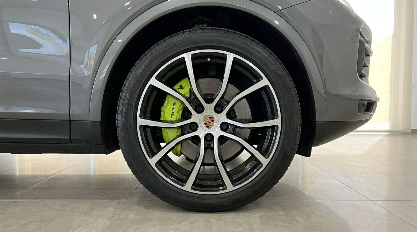 A close-up of the Porsche Cayenne's front wheel, showcasing the black and silver rim and vibrant green brake caliper in Alicante.
