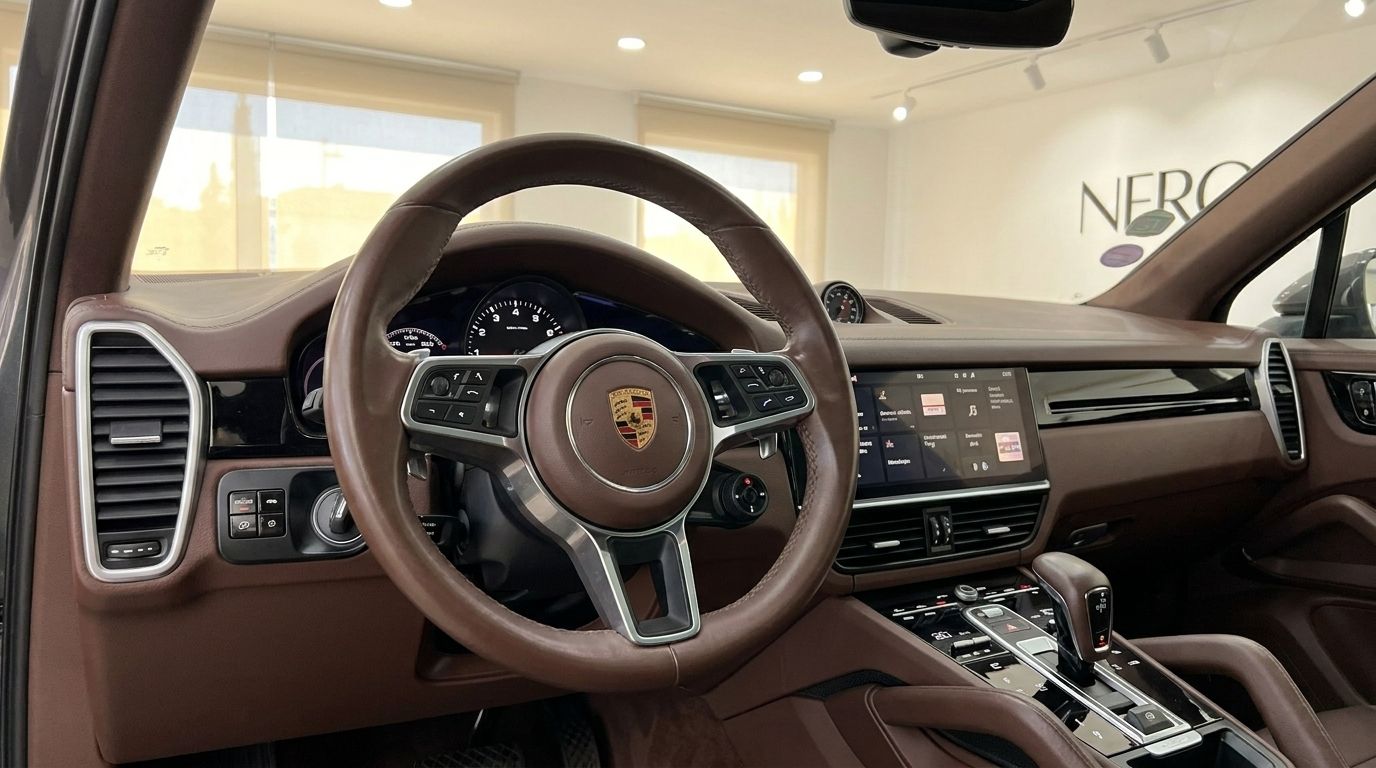 The luxurious brown leather interior of the Porsche Cayenne, featuring the steering wheel, dashboard, and central console, available in Alicante.